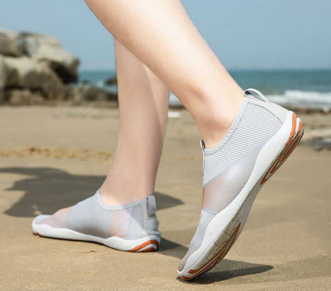 Hombre con zapatos de playa Motion Orange d'Aquashoes marchant sur le sable