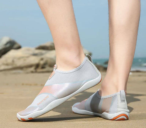 Hombre con zapatos de playa Motion Orange d'Aquashoes marchant sur le sable