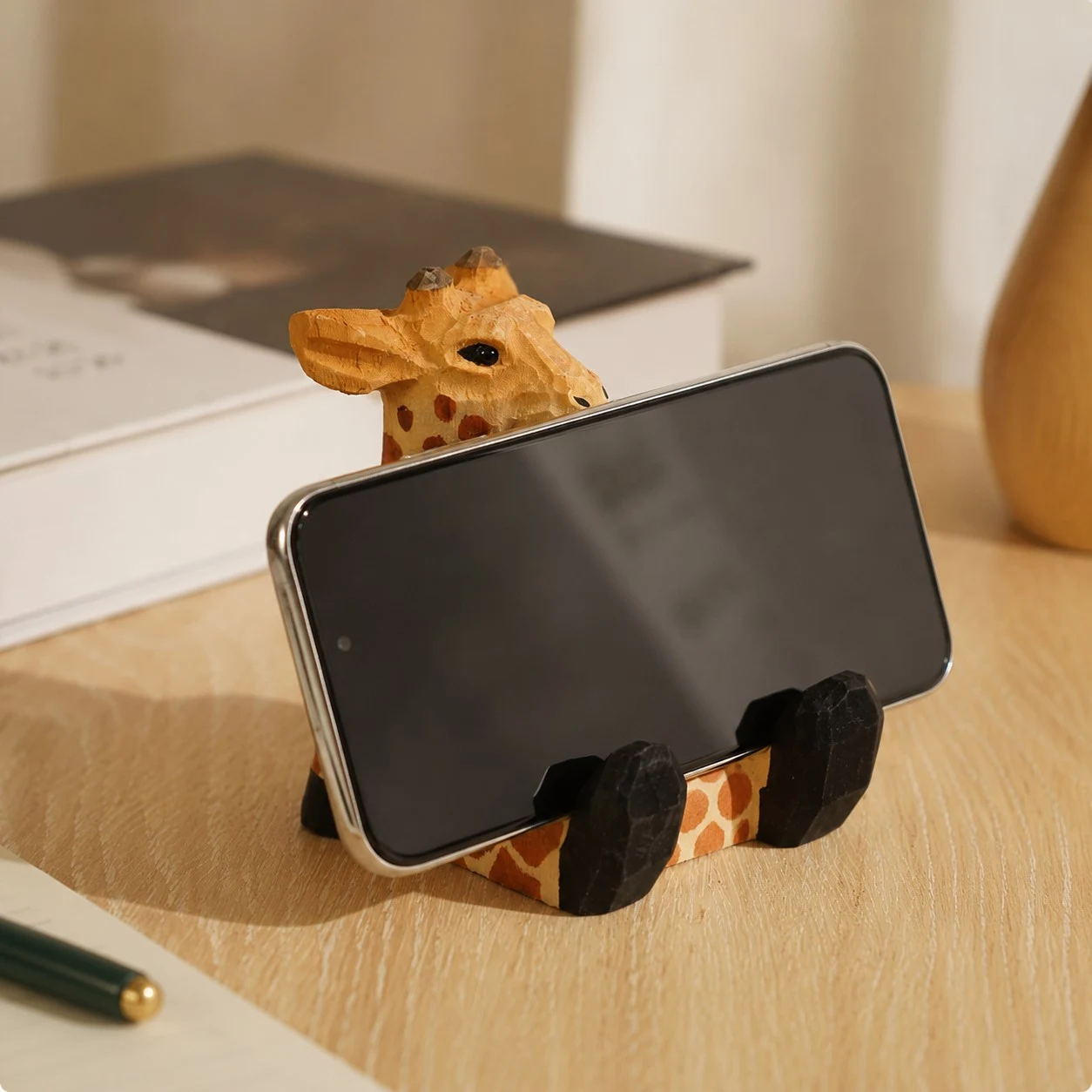 Support de téléphone en bois en forme de girafe, posé sur un bureau