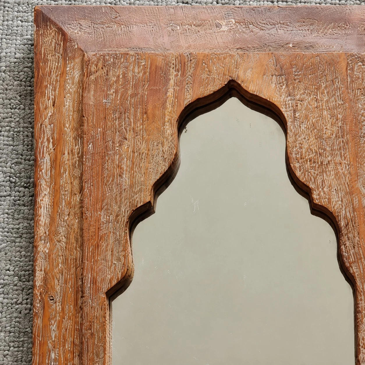 Gros plan sur un détail d'arche sculptée sur le cadre en bois du miroir