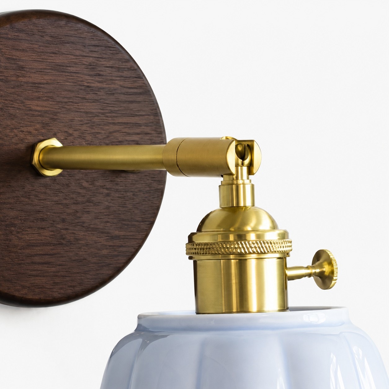 Brass arm and wall base detail of the ceramic wall lamp